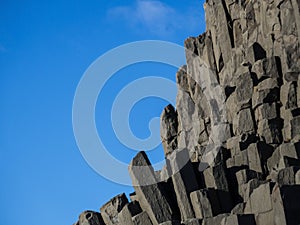 Beautiful natural basalt rock formation near Vik in Iceland rising up into clear blue sky