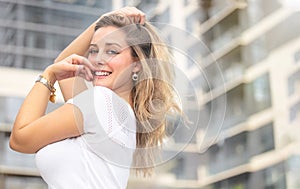 Beautiful natural blonde woman with fun playful flirtatious personality, smiling outside urban city apartment condo building photo