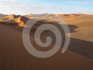 Beautiful natural curved ridge line and wind blow pattern of rusty red sand dune with soft shadow on vast desert landscape