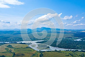 Beautiful natural landscape with aerial view of the green fields of a river with an island and mountains on the horizon
