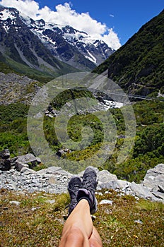 Beautiful natural landscape. Rocks and snowy mountains in the background. Resting on a hike concept. Lying in the grass.