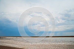 Beautiful natural textural background on a salt lake, river. Salt lake Elton, Russia, before rain and thunder, sunset on the water