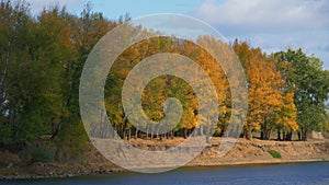 Beautiful nature, autumn landscape - river and forest with bright sunlight, shadows from clouds change on trees, yellow autumn col