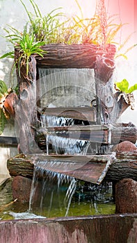 The beautiful nature in garden with waterfall on stone wall. Fountain decorated plants and ferns on stone