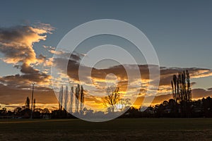 Sunset, sun setting behind trees countryside, grassland