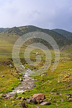 Beautiful nature of Kazakhstan on the Assy plateau in summer. Mountain river, green hills and white yurts