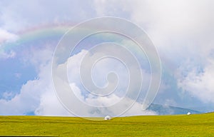 Beautiful nature of Kazakhstan on the Assy plateau. White yurt under the rain clouds and rainbow.