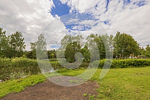 Beautiful nature landscape backgrounds. Lake surrounded with green trees on blue sky with white clouds background.