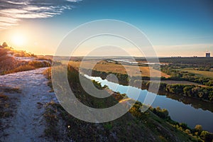 Beautiful nature landscape panorama at sunset time. View from chalk hill or mountain to green meadows and fields with river