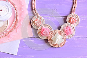 Beautiful necklace for women. Women`s necklace created of ribbons, cords and felt. Materials to create accessory on a wooden table