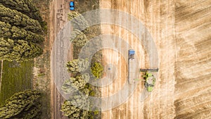 A beautiful new combine harvester dumps grain into a truck trailer on the field. Aerial view