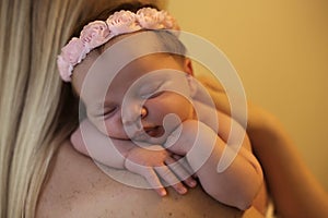 Beautiful newborn baby girl sleeping on mom's shoulders