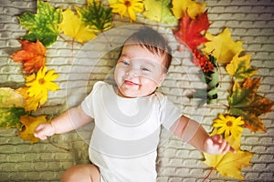 Beautiful newborn baby lies with maple leaves. Autumn concept