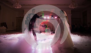 Beautiful newlywed couple first dance at reception, smoke surrondings