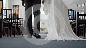 Beautiful newlyweds walking down aisle. Action. Rear view of couple of newlyweds in church. Newlyweds walk down aisle at