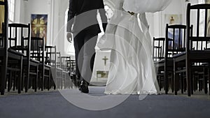 Beautiful newlyweds walking down aisle. Action. Rear view of couple of newlyweds in church. Newlyweds walk down aisle at