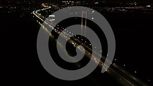 Beautiful night city and a massive bridge, lots of cars, glowing lights, aerial shot