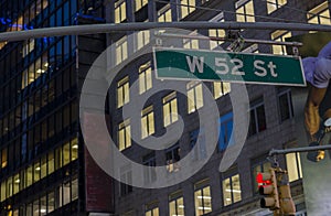 Beautiful night city view of tops of buildings and West 52st Street sign. New York.