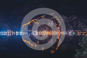 Beautiful night landscape. City in Montenegro Kotor with an old fortress reflected in the bay. Adriatic Sea and travel