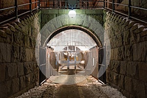 Beautiful night scene of massive stone wall and arch with bright lamp over pedestrian underground tunnel entrance in Stockholm Swe