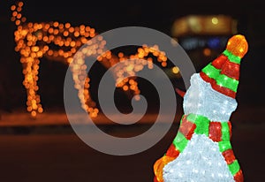 Beautiful night shot of illuminated christmas deer and snowman wearing hat and scarf