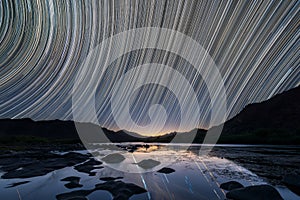 A beautiful night sky landscape with star trails reflecting in the Orange River