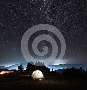 Beautiful night sky over mountain valley with camp tents.
