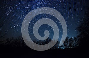 Beautiful night sky, spiral star trails and forest