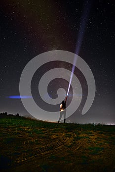 Beautiful night sky with stars and silhouette of a standing alone woman on the mountain with a lantern. Blue milky way