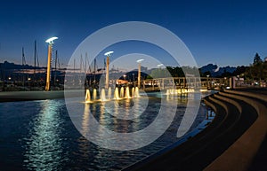 Beautiful night view of fountains, streetlamps at port of Ouchy, Lausanne, Switzerland. Landscape and reflection in water