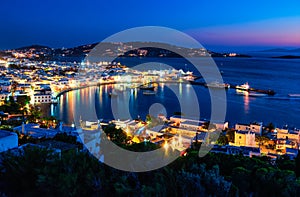 Beautiful night view of Mykonos, Greece, ships, port, whitewashed houses. Town lights up. Vacations, leisure, nightlife