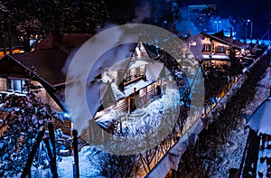 Beautiful night winter christmas landscape. View of snowy village houses lit by warm light from window