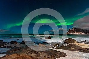 Beautiful Northern Lights in Lofoten Island in Norway. Aurora Boreal over the beach. Majestic green night sky