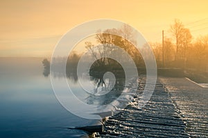 A beautiful Norwegian autumn scenery. Misty morning on a lake. Water flowing over the dam, waterfall.