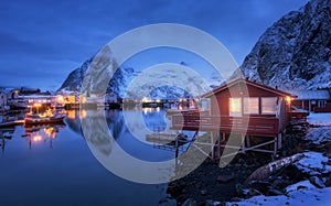 Beautiful norwegian Rorbu on sea cost and snowy mountain at night
