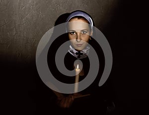 Beautiful nun with a candle reading the Bible. religious concept