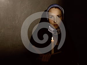 Beautiful nun with a candle reading the Bible. religious concept