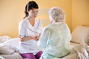 Beautiful nurse holding hand of old senior patient and comfort h