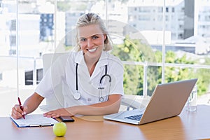 Beautiful nurse writing on a notepad on her desk