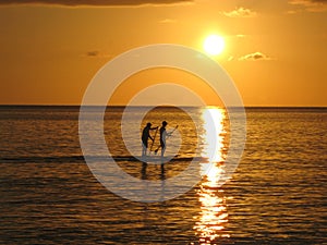 A beautiful tropical sunset over the ocean with paddle boarders photo