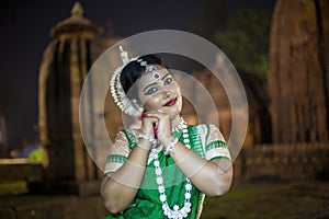 Beautiful Odissi dancer looks at the mirror during the Odissi dance recital against the backdrop of Mukteshvara Temple sculpture.