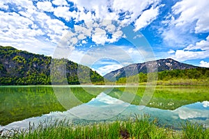 Beautiful Offensee lake landscape with mountains, forest, clouds and reflections in the water in Austrian Alps