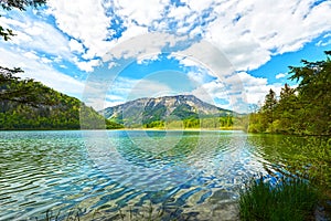 Beautiful Offensee lake landscape with mountains, forest, clouds and reflections in the water in Austrian Alps