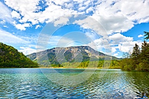 Beautiful Offensee lake landscape with mountains, forest, clouds and reflections in the water in Austrian Alps