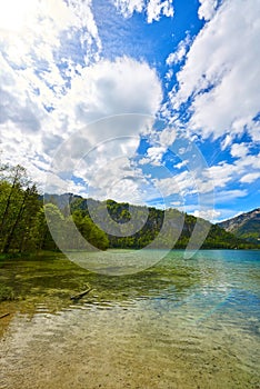 Beautiful Offensee lake landscape with mountains, forest, clouds and reflections in the water in Austrian Alps