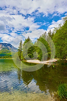 Beautiful Offensee lake landscape with mountains, forest, clouds and reflections in the water in Austrian Alps