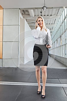 A beautiful office lady talking on the phone and walking