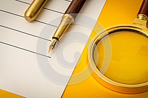 Beautiful office still life on a yellow table with pen and magnifying glass