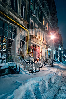 Beautiful old alley covered with snow in the winter with old buildings shot in the night well illuminated by street lamps