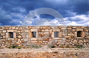 Beautiful old beige stone wall on the background of bright blue sky in Rethymnon, Crete